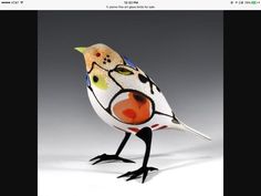 a glass bird sitting on top of a white table next to a gray wall and floor