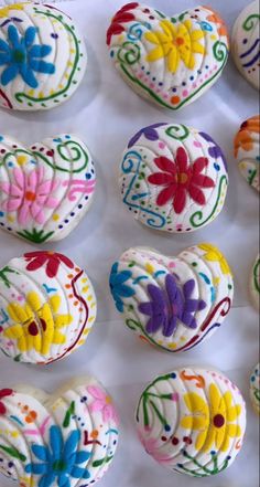 several decorated heart shaped cookies on a white tray with flowers and hearts painted on them