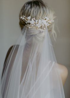 the back of a bride's head with a veil and flowers in her hair