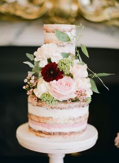 a wedding cake with flowers and greenery on top