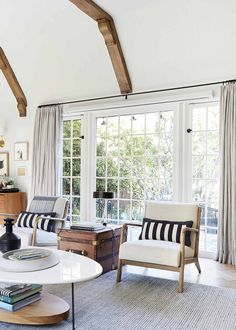 a living room filled with furniture and a window covered in draping next to a wooden table