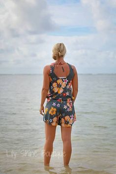 a woman standing in the water looking out at the ocean with her back to the camera