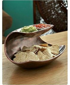 a wooden table topped with two bowls filled with food