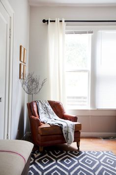 a living room with a chair, rug and window