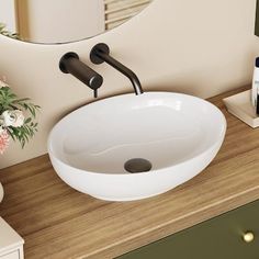 a bathroom sink sitting on top of a wooden counter next to a vase with flowers