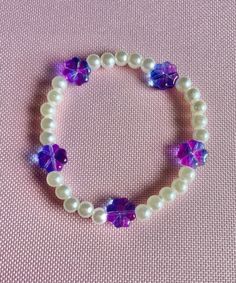 Stretch beaded bracelet white pearl beads with purple glass flower beads. Size Medium. 7 inches in length White Beaded Pearl Bracelet With Flower Shape, White Beaded Pearl Bracelet With Flower Design, White Beaded Flower Pearl Bracelet, Purple Beaded Pearl Bracelets, Purple Flower Shaped Beaded Bracelets, Purple Flower-shaped Beaded Bracelets, Purple Beaded Pearl Bracelet For Gift, Purple Beaded Pearl Bracelet Gift, Purple Beaded Pearl Bracelet As Gift