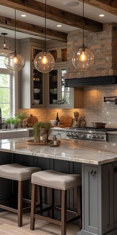 a large kitchen with two stools in front of the island and three lights hanging from the ceiling