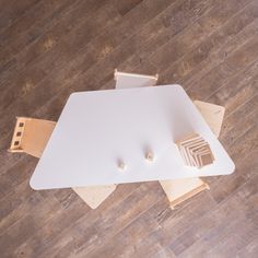 an overhead view of a white table with wooden pieces on it and two chairs around it