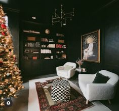 a living room decorated for christmas with black walls and white furniture, a large tree in the corner