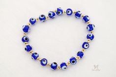 Esta es una auténtica y original pulsera Blue Evil Eye. Una de las razones más comunes para usar el brazalete contra el mal de ojo es protegerse de todo mal o negatividad en su vida.

 El ojo de Nazar se considera uno de los símbolos más poderosos del mundo. Trae protección, paz y buena suerte a tu vida colgando este exclusivo dije de mal de ojo que te mantendrá a salvo de cualquier negatividad.

 Esta pulsera es perfecta para alguien que quiere un regalo económico para ella o para otra persona. Esta pulsera hecha a mano está hecha a mano con cuentas azules de 6 mm y cuentas doradas de 6 mm, cuentas de metal de cobre bañadas en oro falso. Todos los materiales son duraderos y durarán años. Puedes usarlo con cualquier atuendo o ponerlo en la mesa de tu oficina para traerte buena suerte. Blue Beaded Bracelets With Evil Eye, Blue Evil Eye Jewelry For Meditation, Symbolic Blue Bracelet Jewelry, Blue Hypoallergenic Spiritual Bracelets, Blue Adjustable Evil Eye Bracelet, Adjustable Blue Evil Eye Bracelet, Adjustable Blue Symbolic Bracelet, Adjustable Blue Evil Eye Bracelet For Spiritual Purposes, Adjustable Blue Spiritual Evil Eye Bracelet