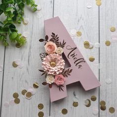 a pink wooden number four with flowers on it and gold confetti around it