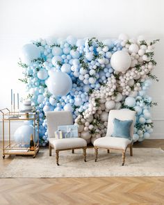 a room with balloons and chairs in front of a wall that has blue and white balls on it