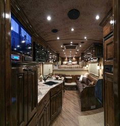 the interior of a motor home with wood paneling and cabinets, including couches