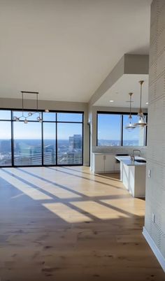 an empty living room with large windows overlooking the city