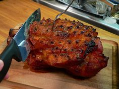 a large piece of meat sitting on top of a cutting board next to a knife and fork