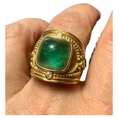 Large, ornate Byzantine style cushion shaped emerald green tourmaline, diamond and 18K yellow gold statement ring. High quality, impressive ring very similar to the Elizabeth Gage Templar ring- this ring has been sized and the signature may have been removed in the process. The cushion shaped cabochon tourmaline measures 12.5mm by 12.5mm by 8.2mm, approximately 10.6 TCW, beautiful emerald green color with natural attractive inclusions, surrounded by collet-set round diamonds, gold bead details, crescent moon with gold bead details motif at the top and base of ring setting, textured and highly polished gold finishes. A stunning statement ring. Size 7US Very good condition, sizing to the back of the ring with slight waviness Ring dimensions: 21mm by 21mm Marks: 18K Byzantine Rings, Gold Statement Ring, Jewelry Fashion Trends, Cabochon Ring, 18k Yellow Gold Ring, Yellow Gold Ring, Green Tourmaline, Yellow Gold Rings, Cocktail Rings