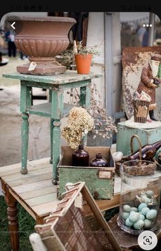 an old table with baskets, vases and other items on it in front of a store