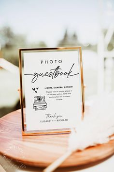 a photo guest book sitting on top of a wooden table next to a white feather