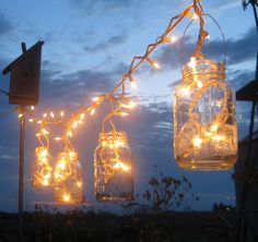 mason jars with fairy lights hanging from them on a string in front of the sky