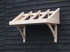 a wooden shelf on the side of a black wall with wood slats attached to it