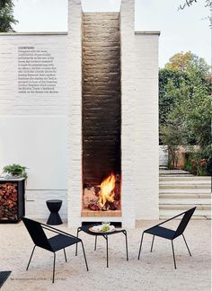 an outdoor fireplace with two chairs and a table in front of it on the patio