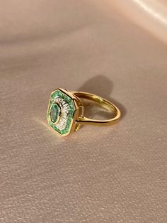 Gorgeous 9k yellow gold emerald and diamond deco style target ring. This vintage inspired piece features 4 small round cut diamonds and 19 oval + round cut emeralds. The emeralds have natural inclusions and carbon spots and range in color. The very small diamonds are set in an illusion-type setting: north, south, east and west.Weight: ~ 3 gramsHallmarks: 375 for 9k, anchor for Birmingham EnglandHead of the ring: 12.75 mm x 11.75 mmEmerald: 5.5 mm x 3.5 mm oval cut natural (central), 18 x 2 mm na Art Deco Target Ring, Unique Engagement Rings Non Traditional Vintage, Target Ring, Art Deco Rings, Art Deco Emerald Ring, Tiny Diamond, North South, Deco Ring, To Infinity And Beyond