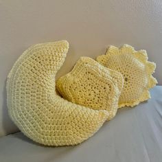 three crocheted yellow pillows on a white bed