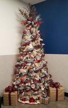 a decorated christmas tree in an office cubicle with presents on the floor next to it