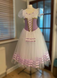 a dress made out of tulle with pink ribbon and bows on the waistline