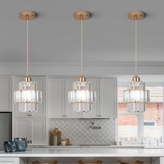 three lights hanging over a kitchen island with stools in front of the counter top