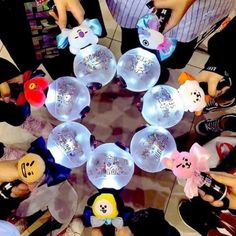 a group of people standing in a circle holding up plastic balls with teddy bears on them