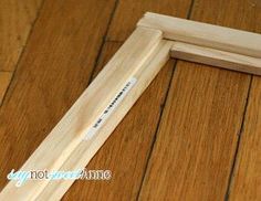 a wooden frame laying on top of a hard wood floor next to a pen and eraser