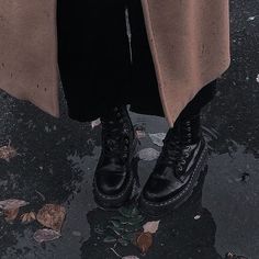 a person standing in the rain wearing black boots