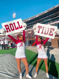 two cheerleaders holding up signs at a football game