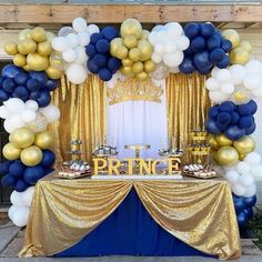 a table topped with blue and gold balloons next to a sign that says prince on it