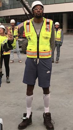 a man in safety vest holding a baseball bat with other people standing around behind him