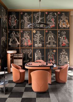 a dining room with black and white wallpaper, orange chairs and a round table