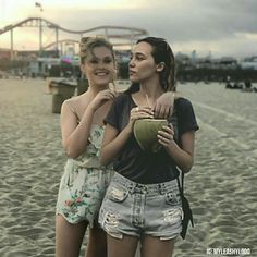 two young women standing on the beach next to each other