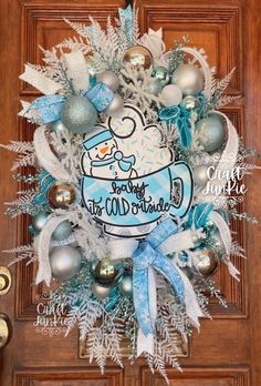 a christmas wreath on the front door with snowflakes and ornaments hanging from it