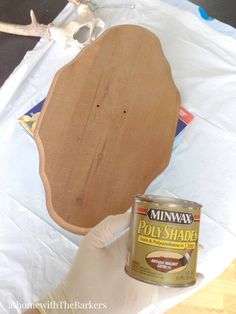 a wooden sign sitting on top of a table next to a can of paint and a deer skull