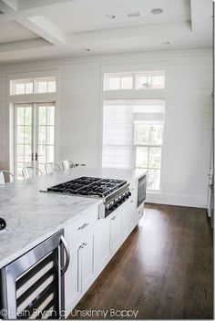 a kitchen with white cabinets and marble counter tops, along with an island in the middle