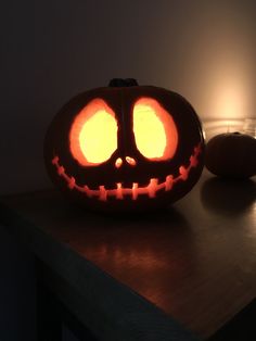 a pumpkin carved to look like a jack - o'- lantern sits on a table