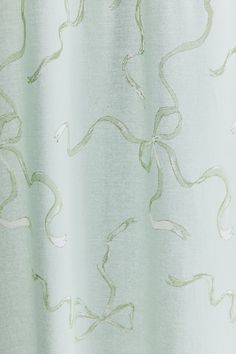 a white curtain with green swirls on it