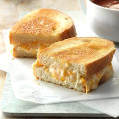 two grilled cheese sandwiches sitting on top of a piece of paper next to a cup of coffee