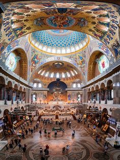 the inside of a church with many people standing in it and paintings on the ceiling