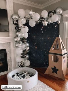 a balloon arch with silver and white balloons in the shape of houses, stars and rockets