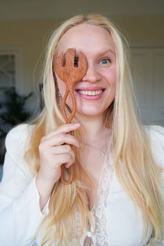 a woman holding up a wooden object to her face with the word love spelled on it