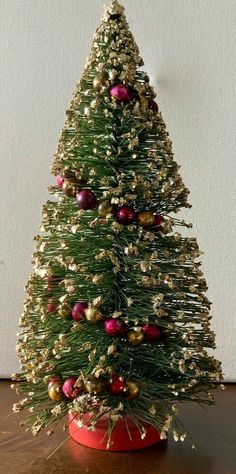 a small christmas tree in a red pot with gold and red ornaments on the top