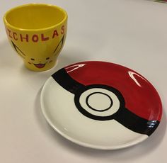 a pokemon themed plate next to a yellow and red coffee cup on a white table