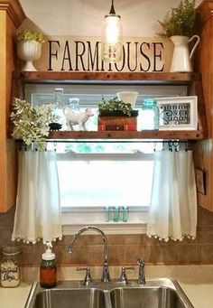 a kitchen sink under a window with the word farmhouse on it's shelf above it